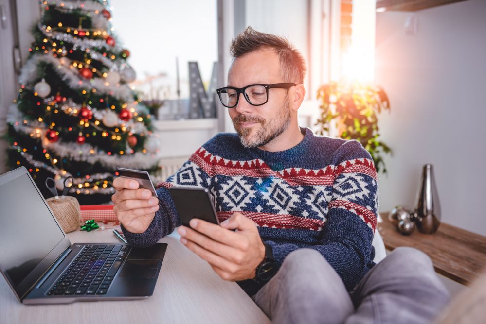 Man in Christmas jumper with credit card and mobile phone