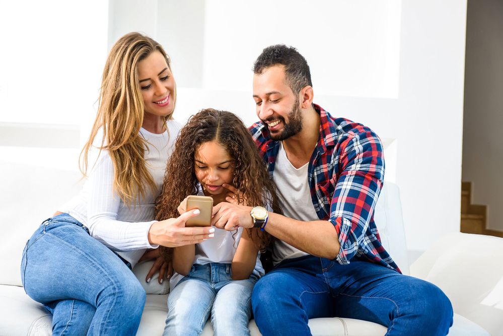 2 adults and child looking at mobile phone