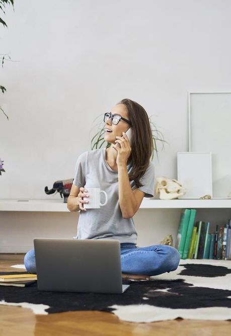 Woman on phone and laptop drinking tea