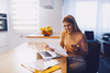 Woman reading bill beside laptop