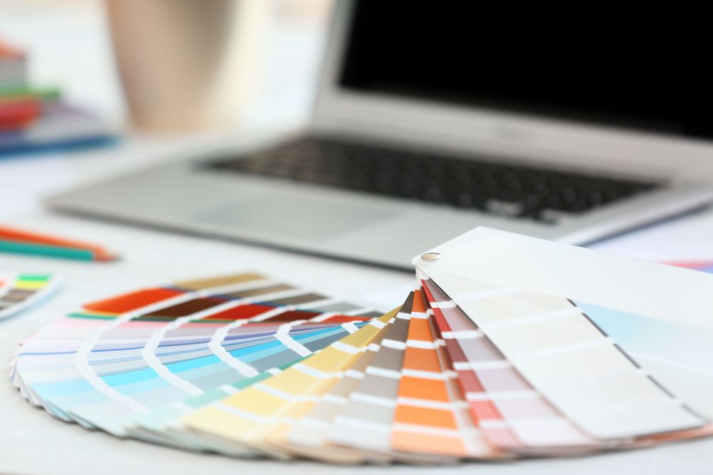 A laptop with a paint colour guide spread out in front of it